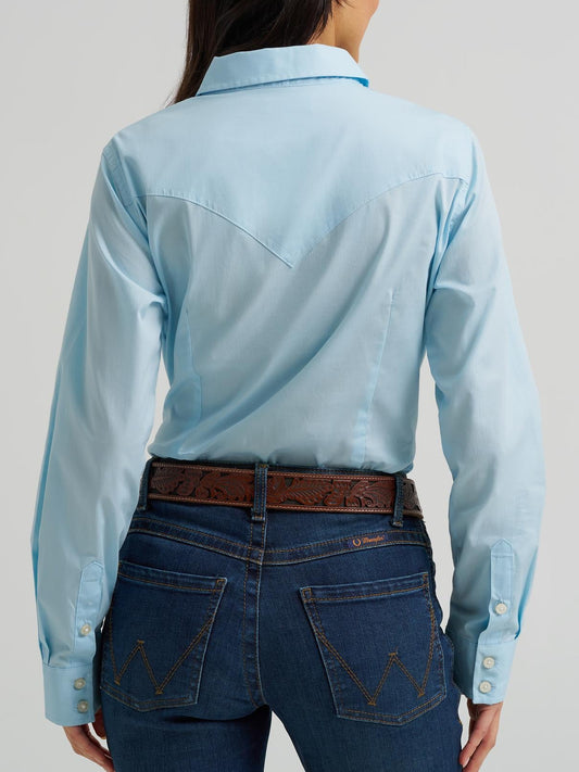 Person wearing a light blue shirt and dark blue jeans on a plain background