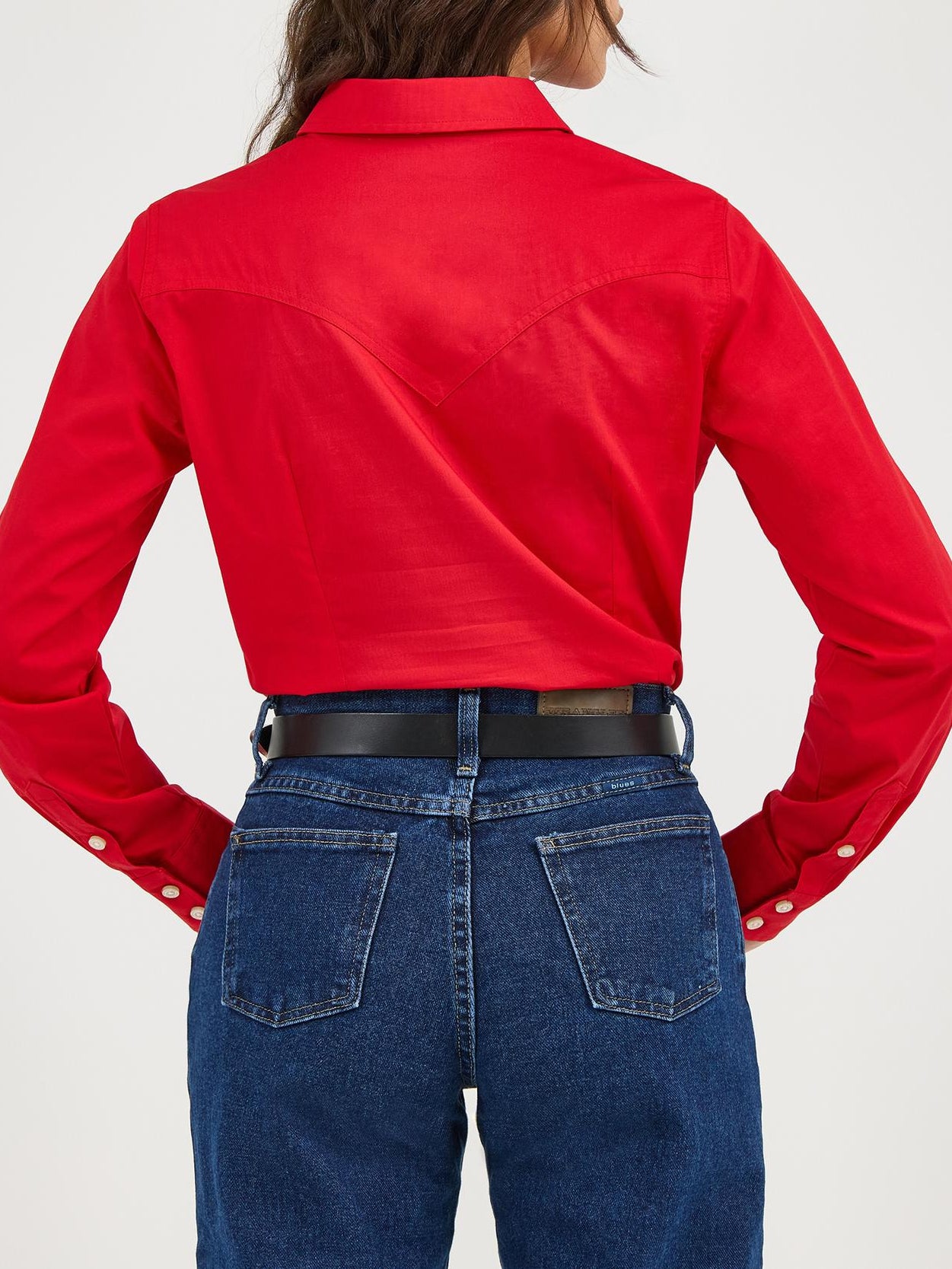 Person wearing a red shirt, blue jeans, and a black cowboy hat on a white background