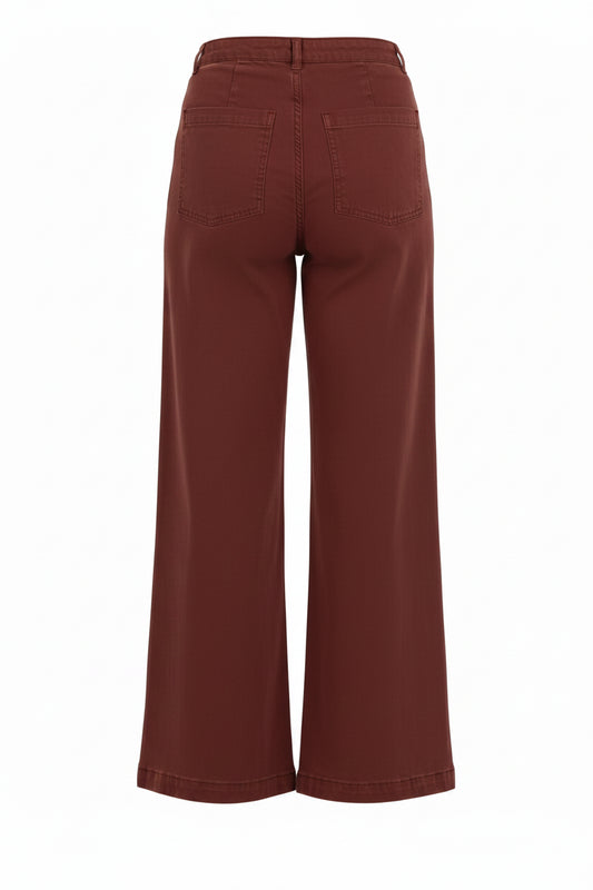 Rust red wide-leg pants shown from the back on a model, paired with a white top and beige sneakers, against a plain white background.
