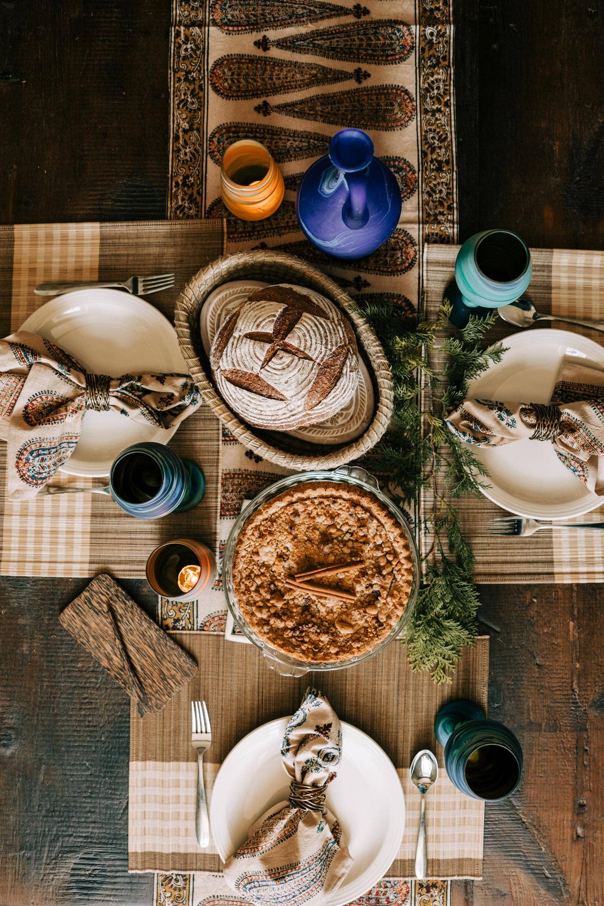 Overhead view of the Toasty Bread Basket with bread on a table set with plates, colorful glasses, and a pie