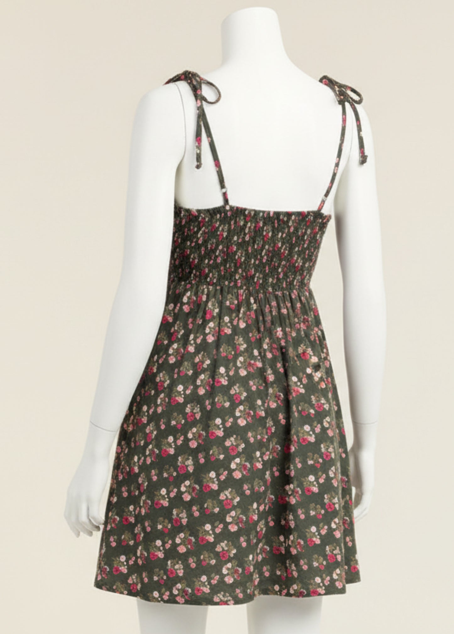 Woman wearing a floral dress with thin straps on a plain background