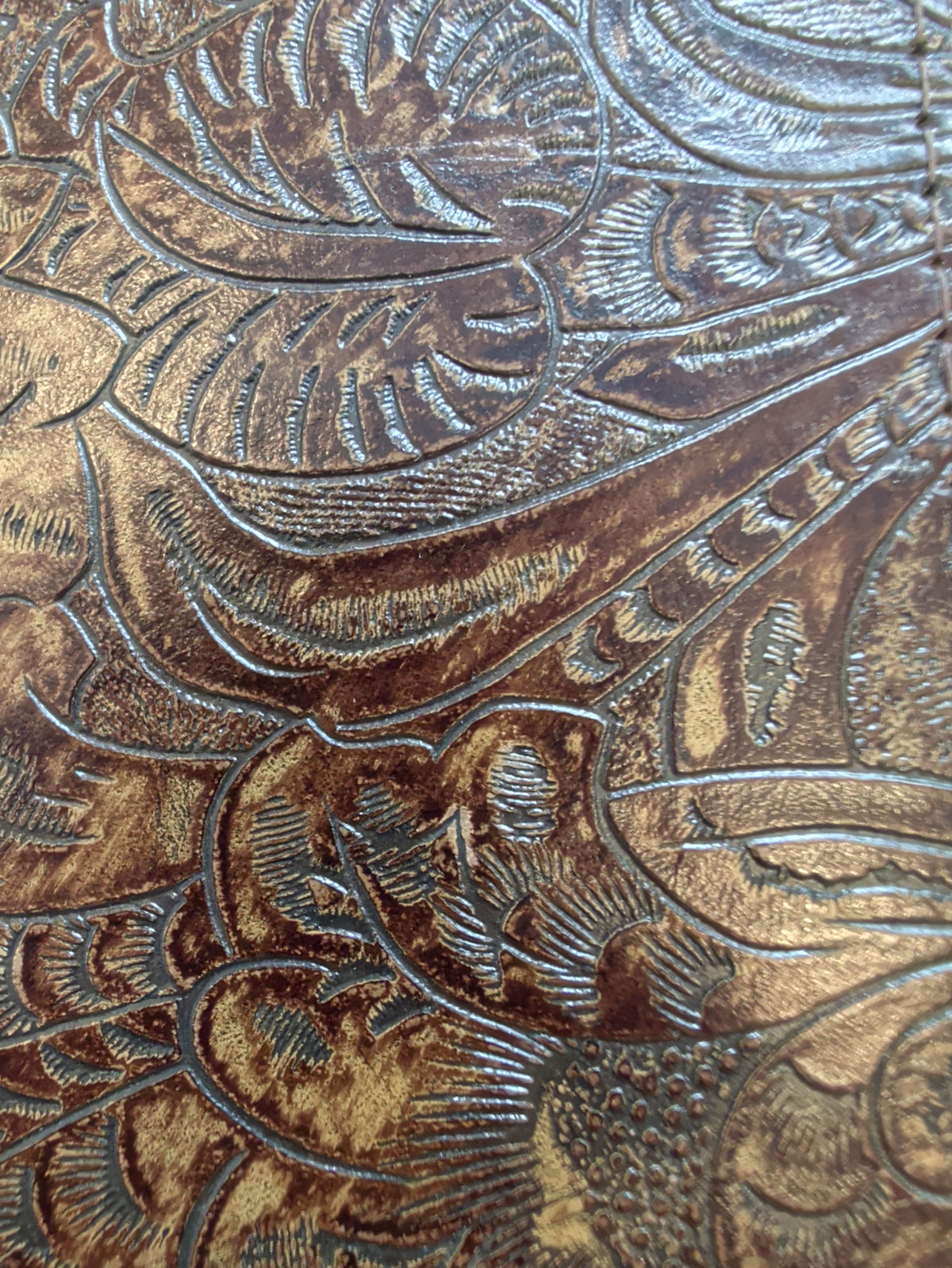 Brown leather journal cover with an embossed floral scroll pattern
