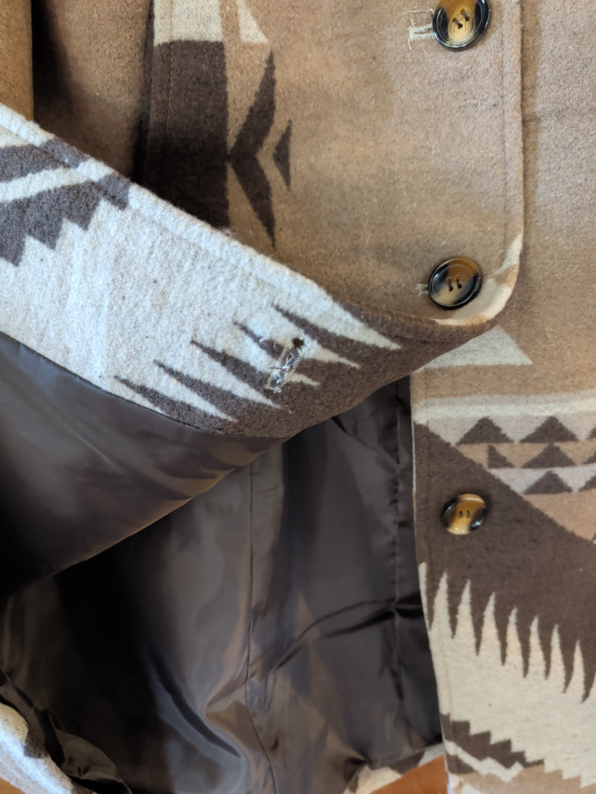 Inside view of the coat showing dark lining, button-front closure.