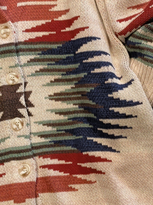Close-up of cream cardigan showing Southwestern knit pattern in rust, navy, sage, and brown with cream front buttons.