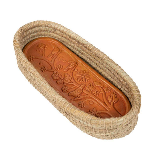 Toasty Long Bread Basket with a bird-and-flower patterned terracotta warming insert inside a natural woven basket
