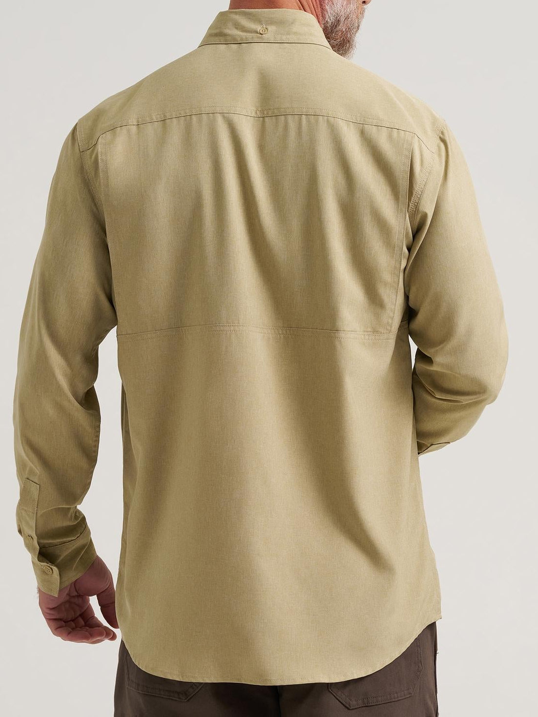 Man wearing a beige shirt and brown pants on a light gray background