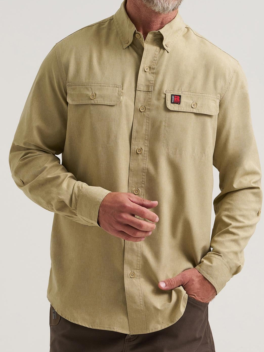 Man wearing a beige shirt with a logo on a plain background