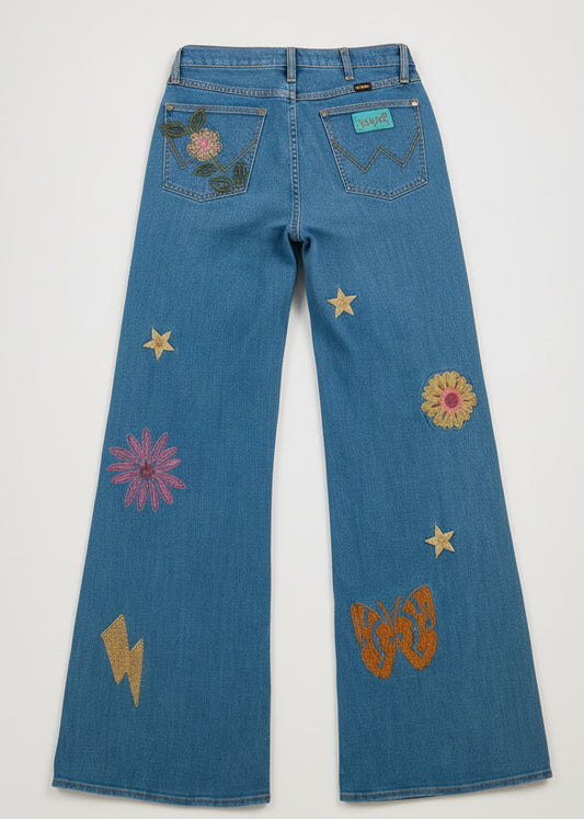 Person wearing a blue denim outfit with floral and star patterns on a plain background