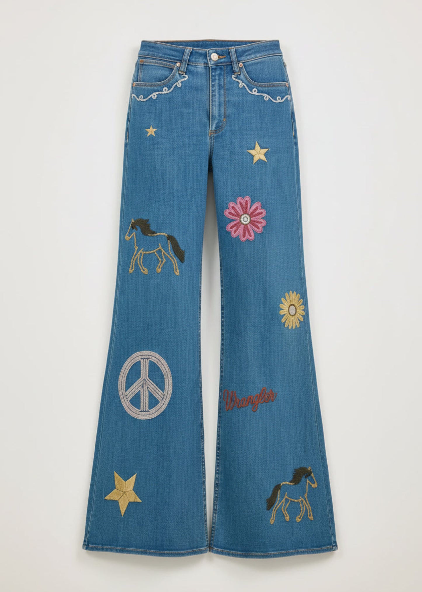 Person wearing a denim outfit with embroidered designs on a plain background