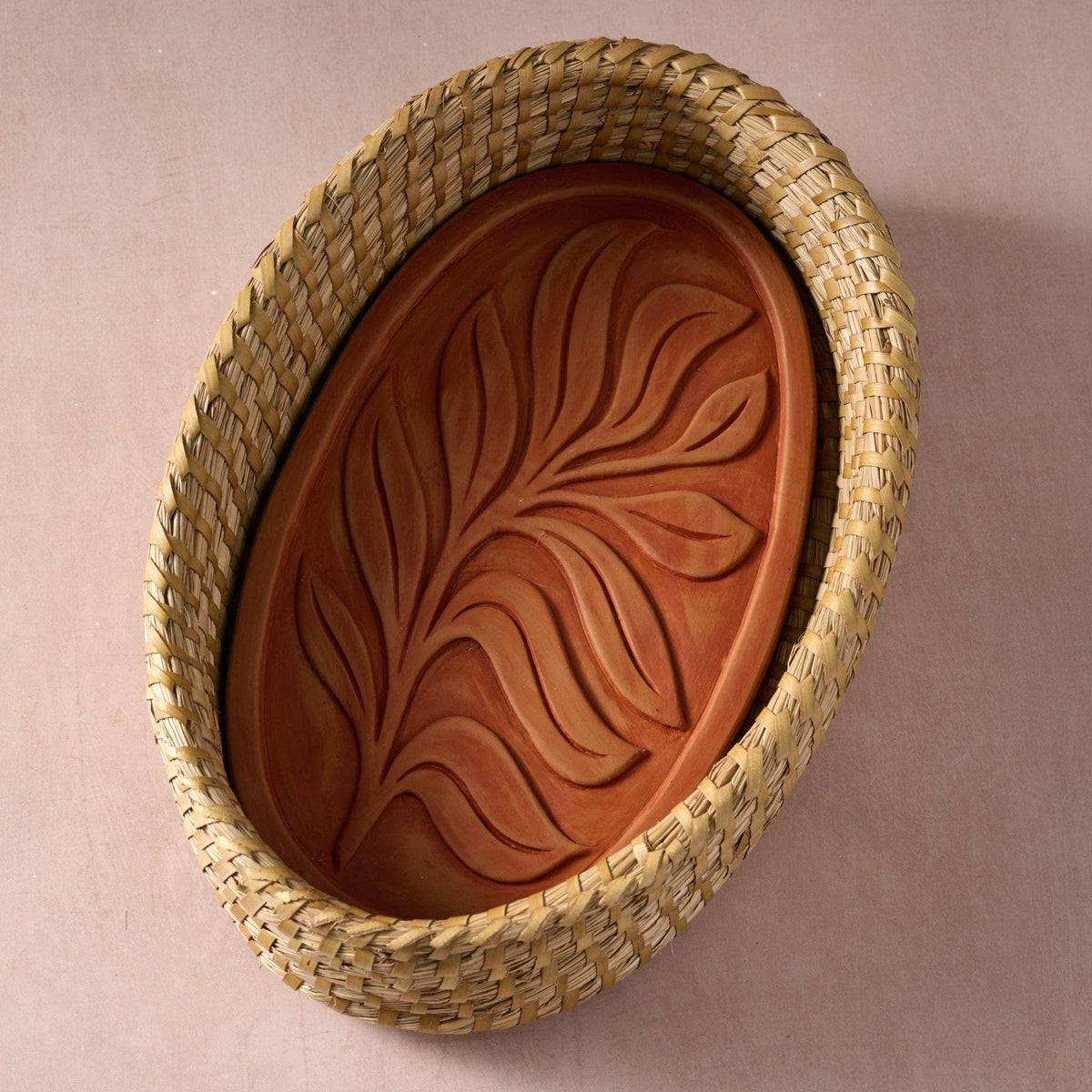 Gama Oval Leaf Bread Warmer viewed from above, with a leaf-patterned terracotta insert inside a woven kaisa grass basket