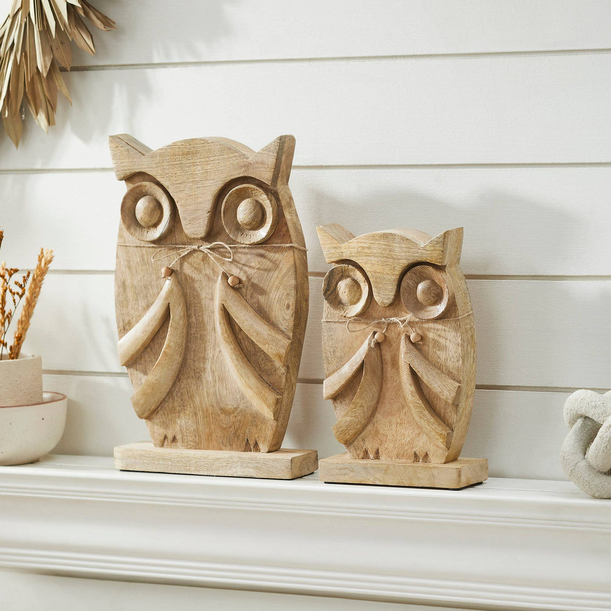 Natural mango wood owl figurines styled on a white mantel against a shiplap wall