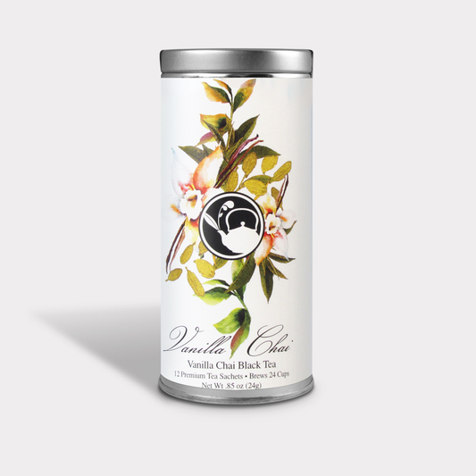 Vanilla Chai Black Tea tall white tin with botanical leaves, pale flowers, vanilla pods, and a black-and-white teapot logo