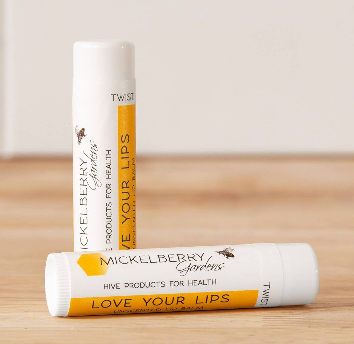 Two Mickelberry Gardens Love Your Lips unscented Regular lip balm tubes on a wooden surface

