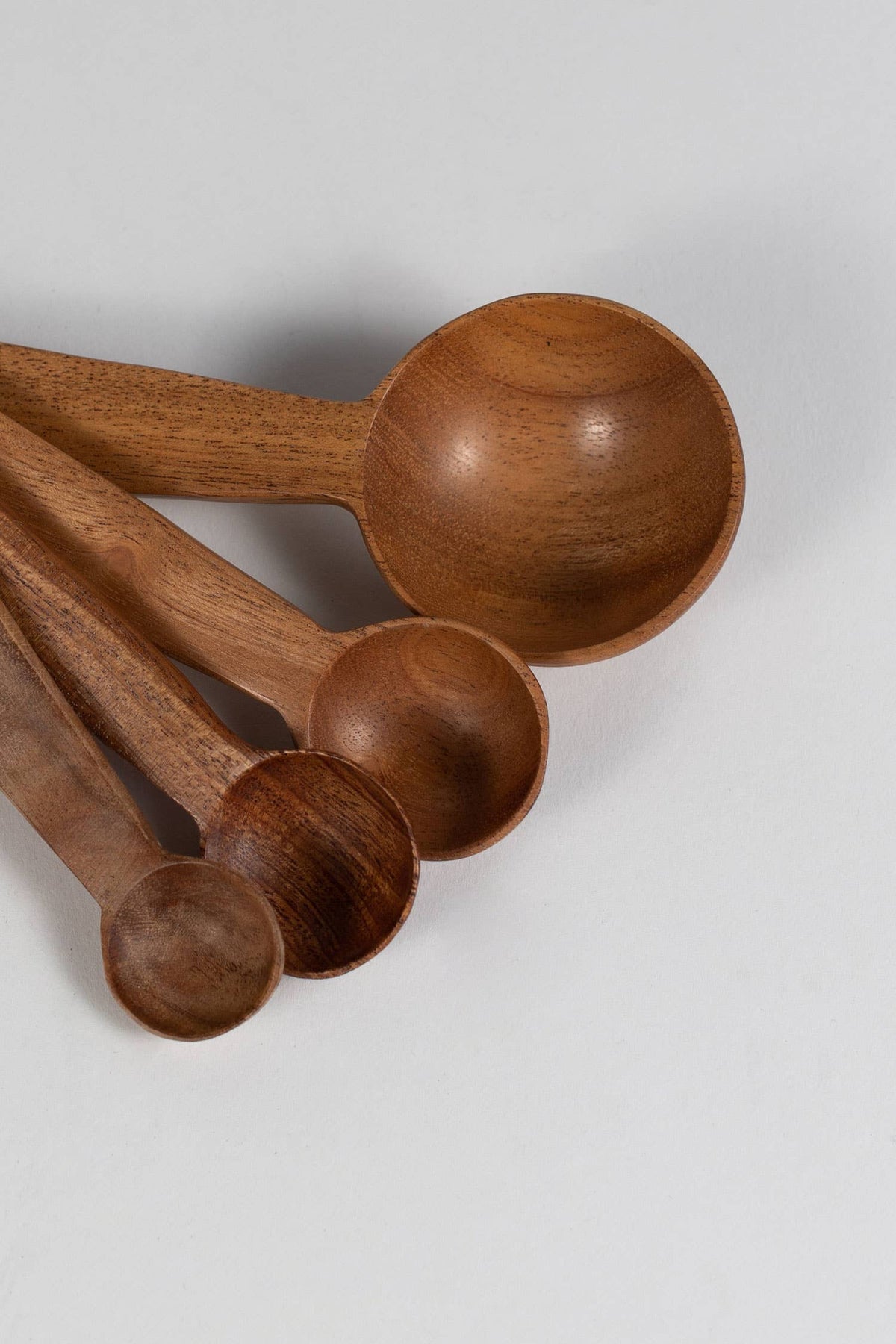 Close-up of four wooden measuring spoon bowls showing their graduated sizes and natural wood grain⠋

