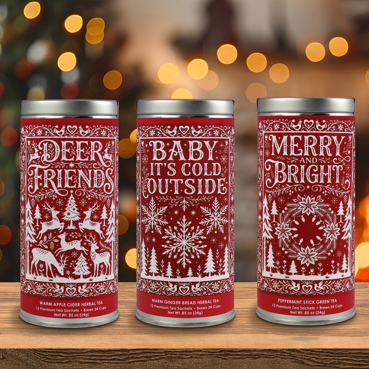 Three red holiday tea tins featuring Deer Friends apple cider, Baby It's Cold Outside gingerbread, and Merry and Bright peppermint