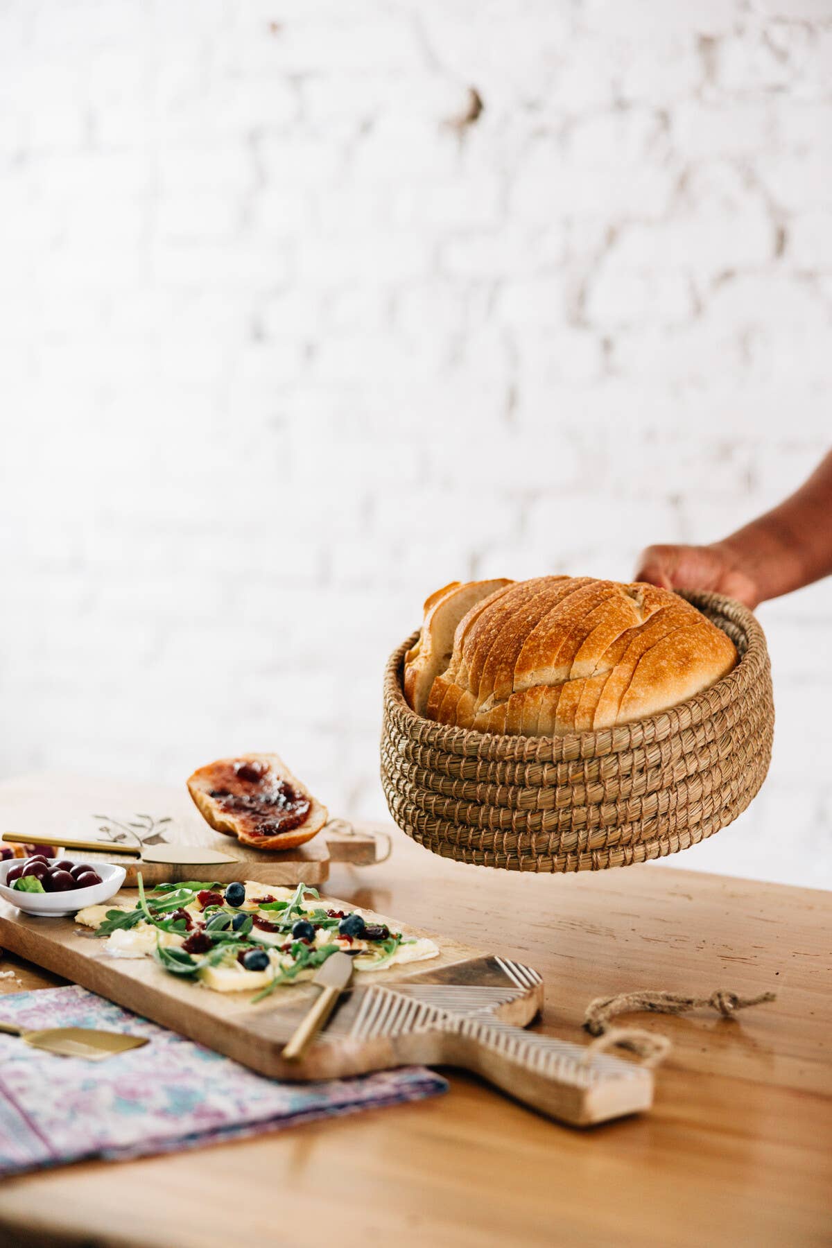 Toasty Round Bread Basket filled with sliced bread being carried to a table with a serving board