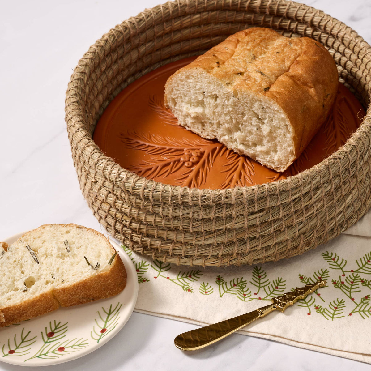 RoseMerry Bread Warmer holding a partially sliced loaf, with a slice of herb bread on a plate beside it