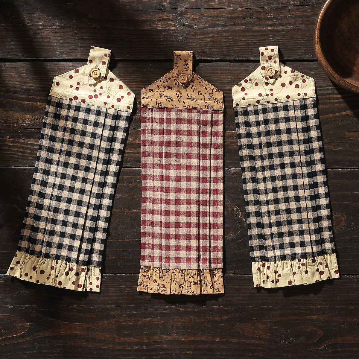 Pip Vinestar button loop kitchen towels with black or burgundy checks, printed trim, and ruffled hems displayed on dark wood.