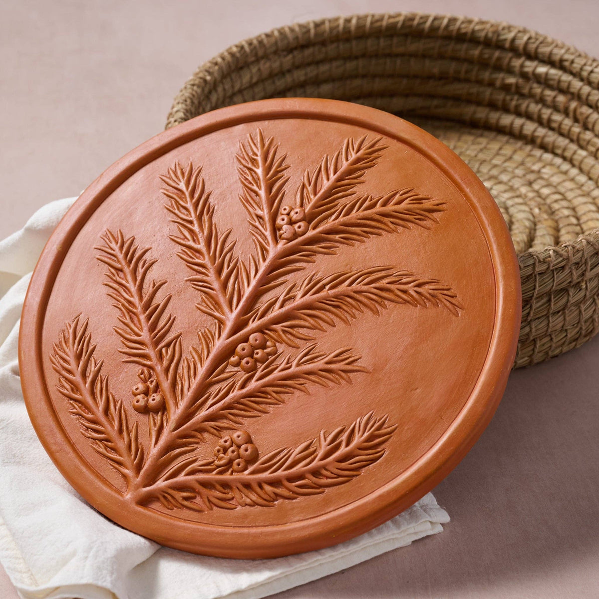 RoseMerry terracotta warming stone displayed outside its woven basket, showing the detailed branch-and-berry design