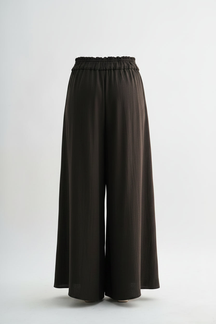 Person wearing brown wide-leg pants on a white background