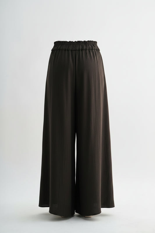 Person wearing brown wide-leg pants on a white background