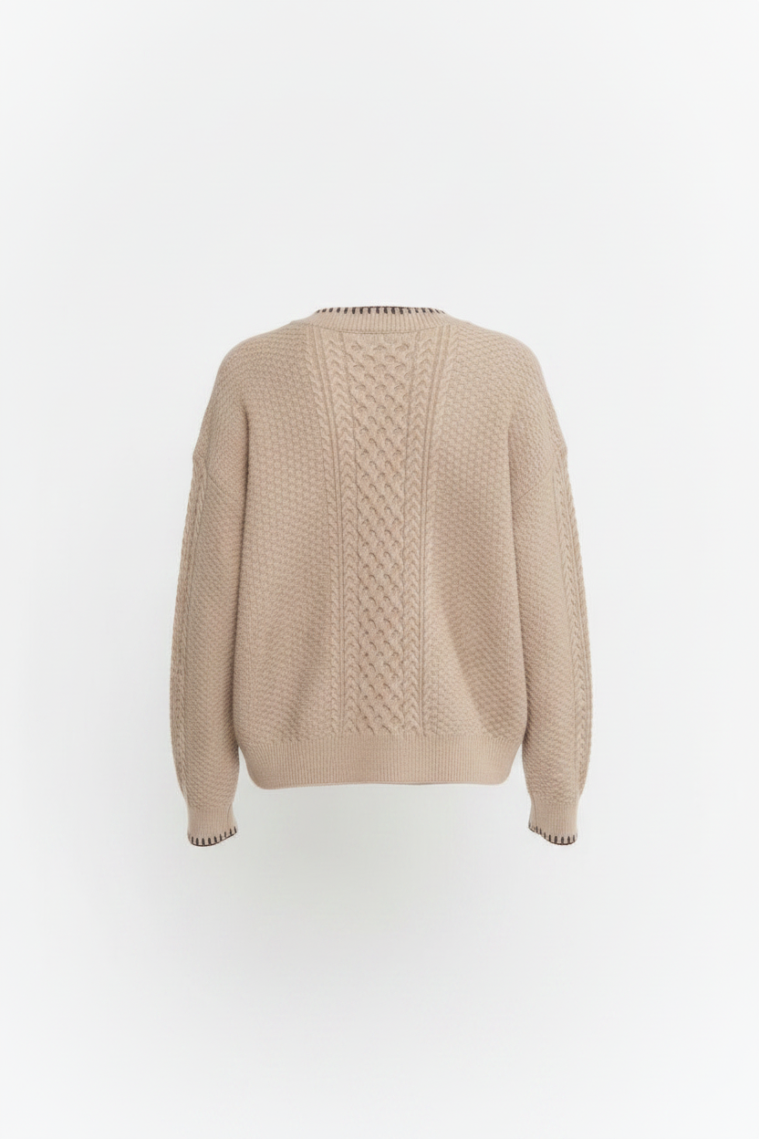 A woman shown from the back wearing a beige cable-knit sweater and dark brown pants against a plain white studio background.