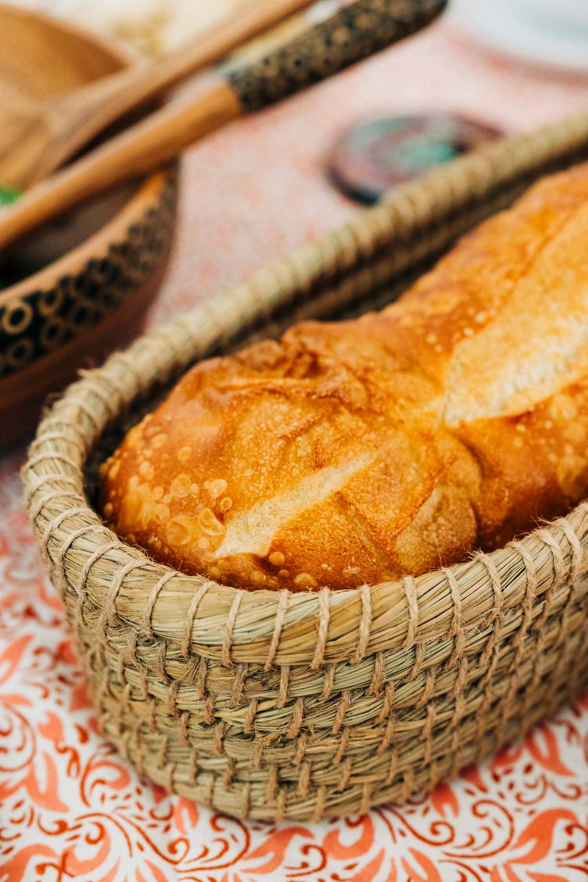 Sliced bread served in the Toasty Long Bread Basket on an orange-and-white patterned tablecloth
