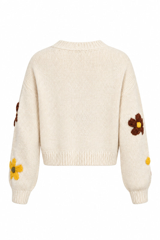 Shown from the back wearing a cream-colored knit sweater with brown and yellow flowers embroidered on the sleeves, against a plain white background.