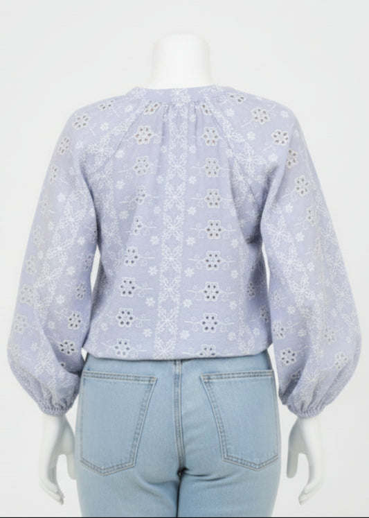 Person wearing a light blue floral blouse and jeans on a white background