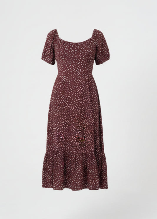 Woman wearing a chocolate dress with white polka dots on a white background