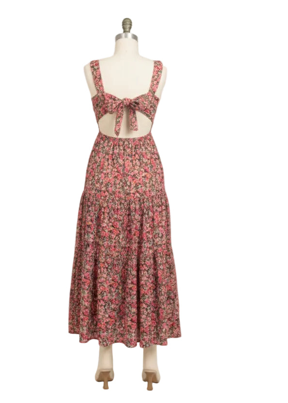 Woman wearing a floral dress with cut-out back on a plain background