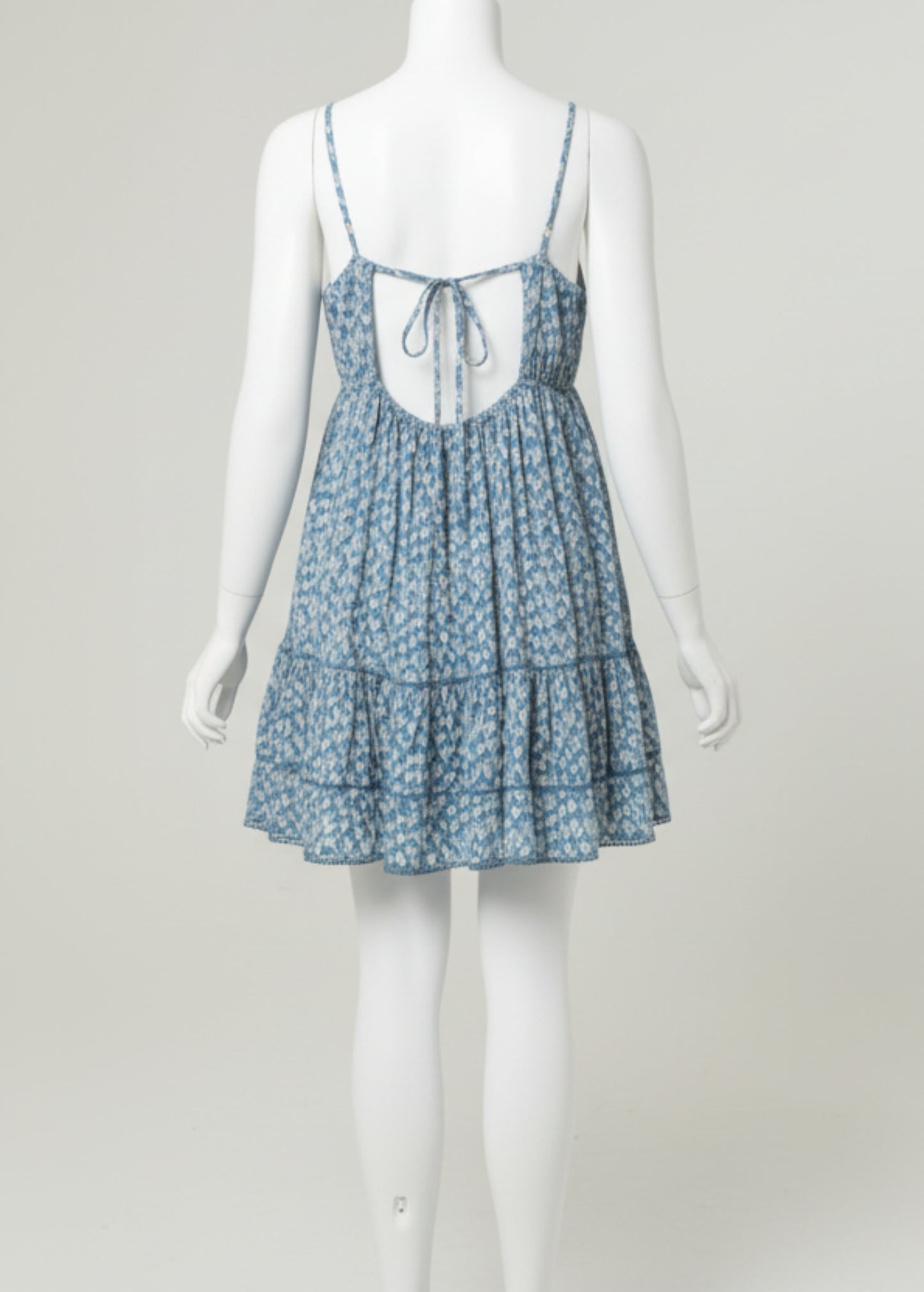Woman wearing a blue floral dress on a plain background