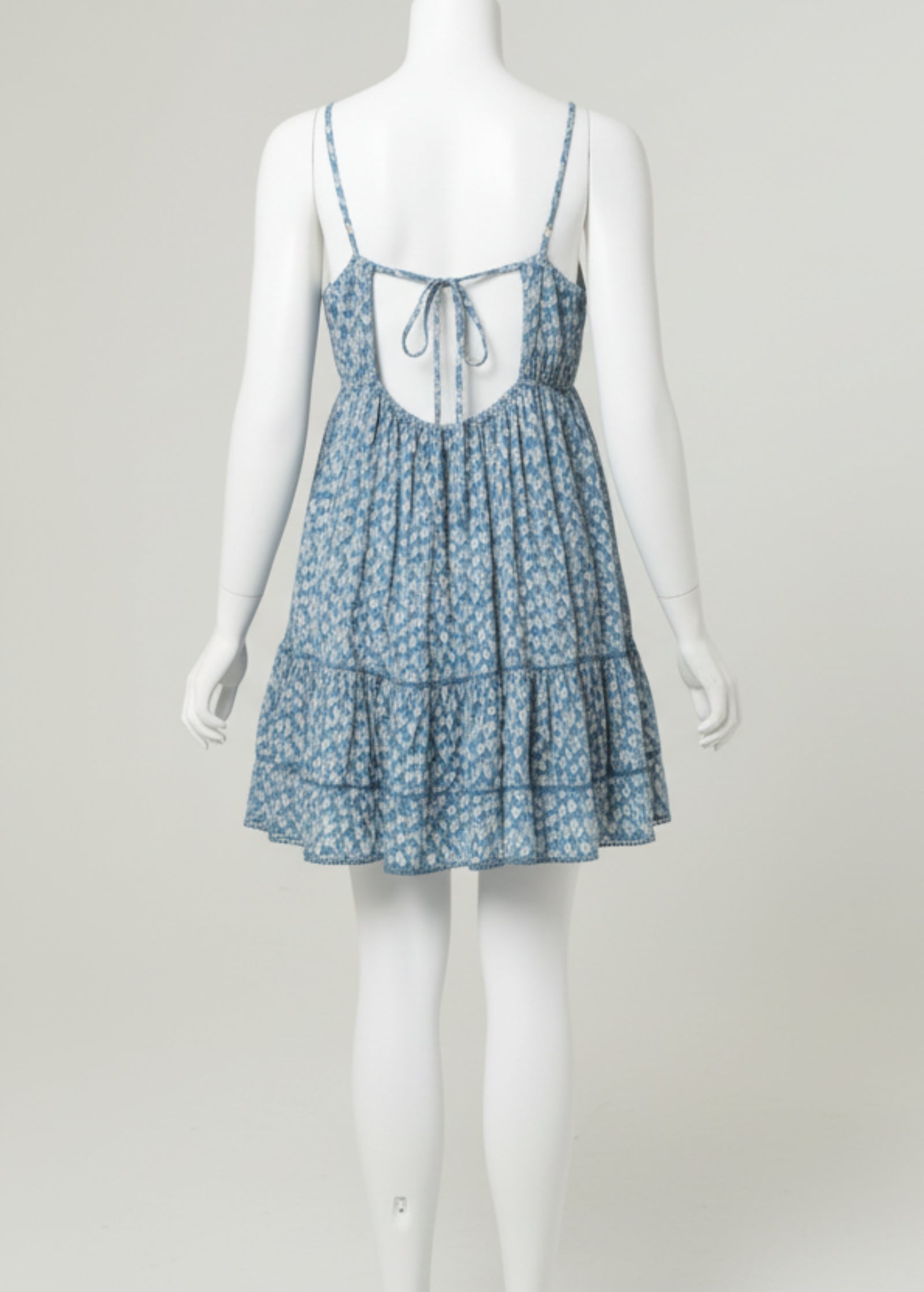 Woman wearing a blue floral dress on a plain background