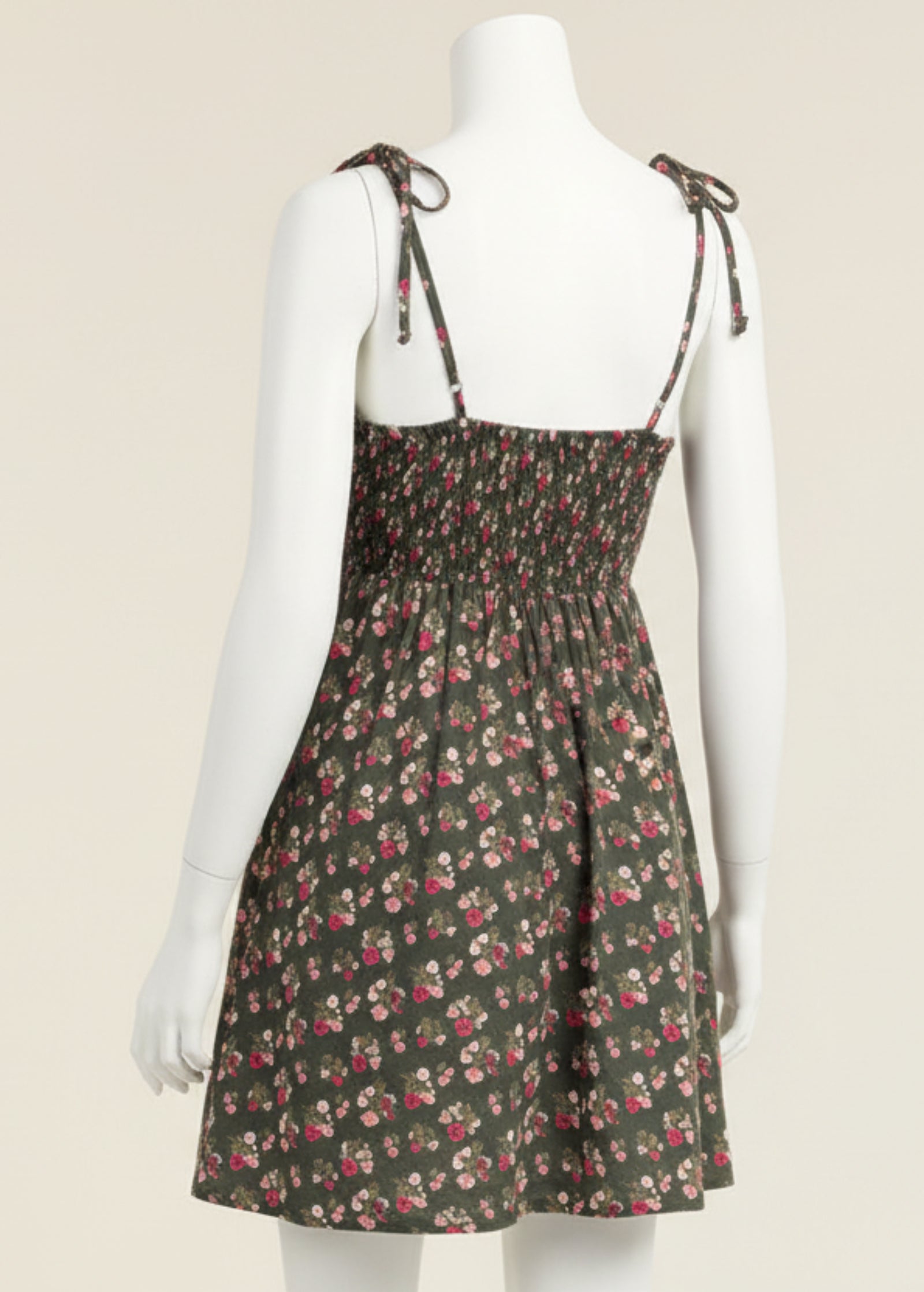 Woman wearing a floral dress with thin straps on a plain background