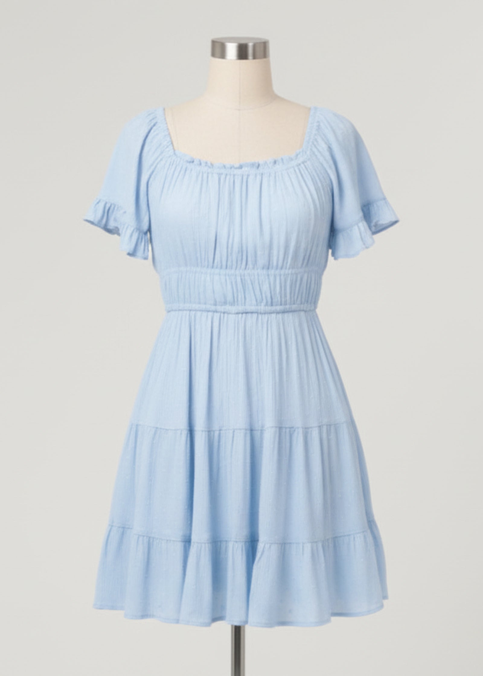 Woman wearing a light blue dress with ruffled sleeves on a plain background