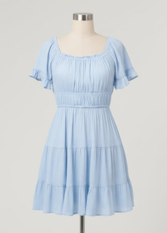 Woman wearing a light blue dress with ruffled sleeves on a plain background