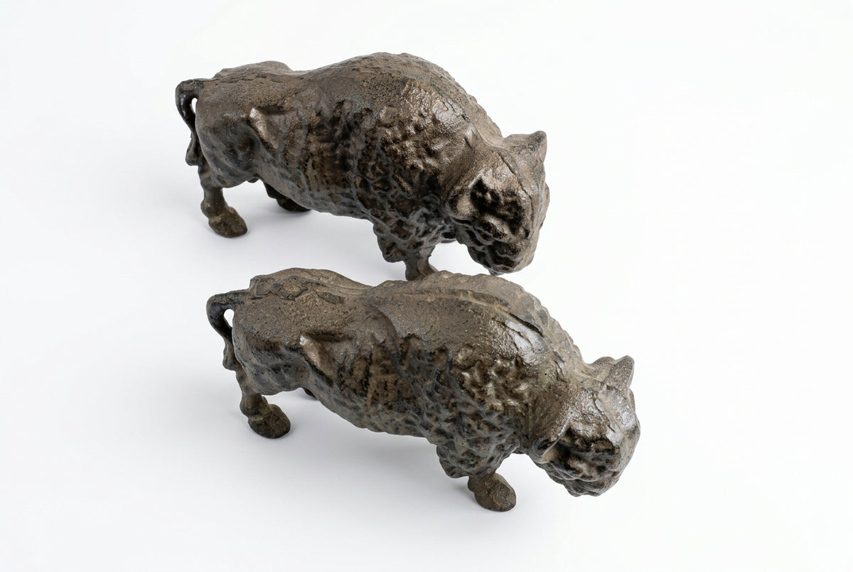Two cast iron buffalo door stops viewed from above, showing textured backs and sculpted details