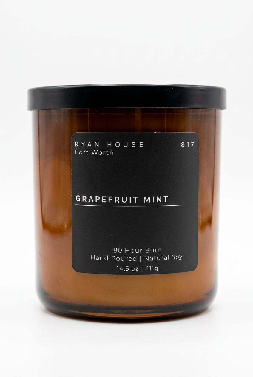 Ryan House Grapefruit Mint candle in an amber glass jar with a black lid and charcoal label showing 14.5 oz.