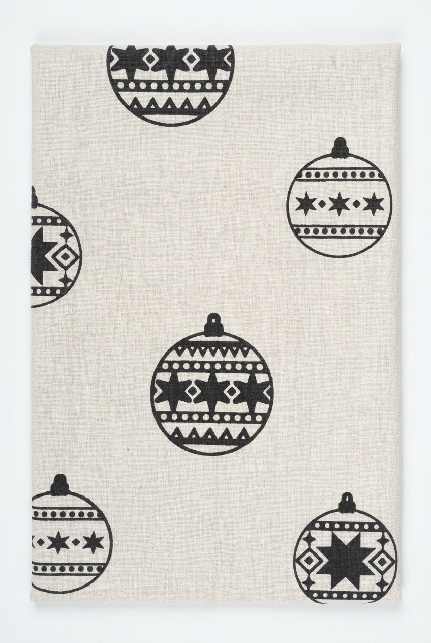 Close-up of gray Christmas ornaments with stars and geometric patterns on an unbleached cotton tea towel.