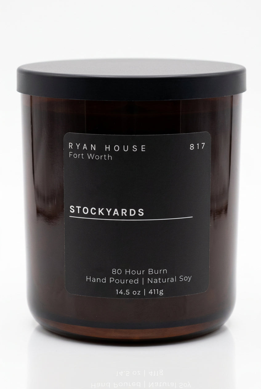  Ryan House Stockyards candle in an amber glass jar with a black lid and charcoal label showing 14.5 oz.