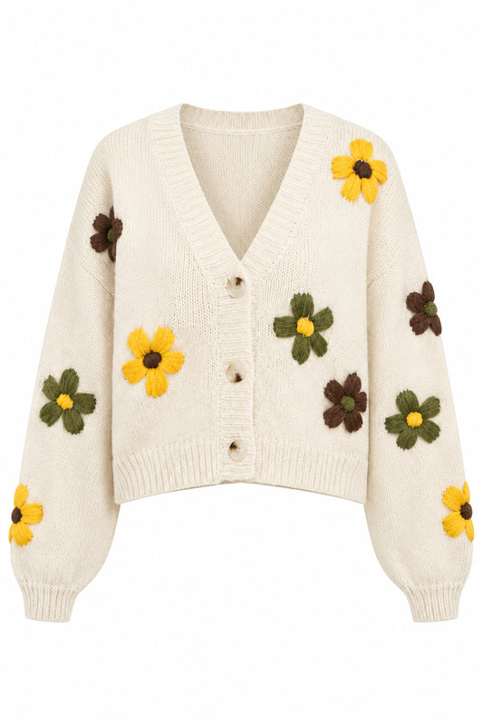 A cream-colored knit cardigan sweater with large yellow, brown and green flower appliqués embroidered with three large buttons.
