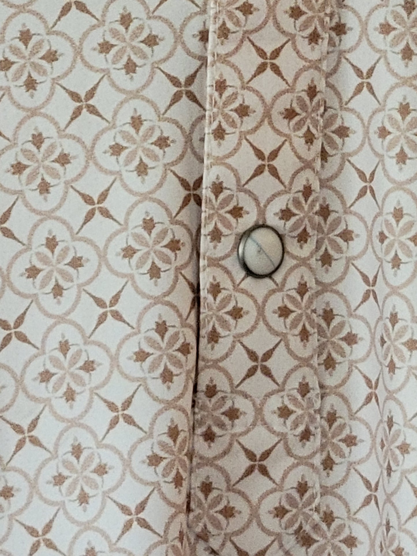 Close-up of a patterned fabric with a button on a beige background