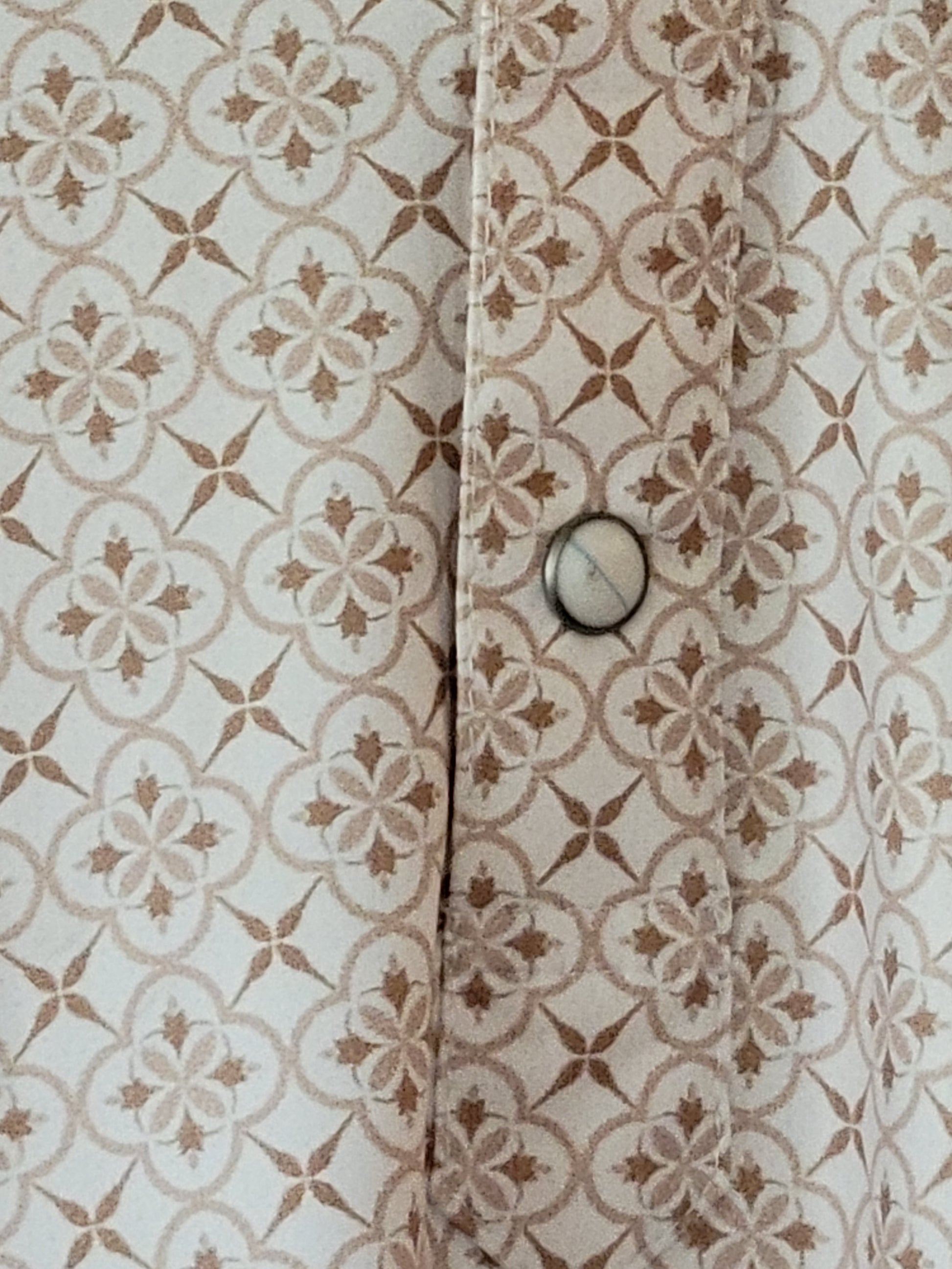 Close-up of a patterned fabric with a button on a beige background