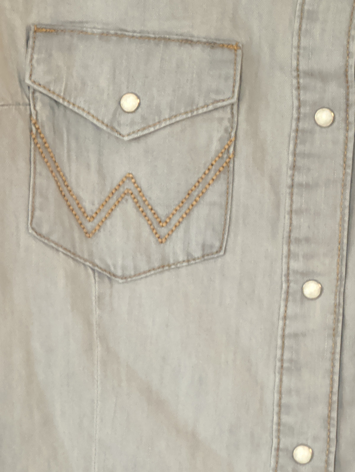 Close-up of the grey denim shirt’s snap-flap chest pocket with contrast W embroidery and snap-front closure.