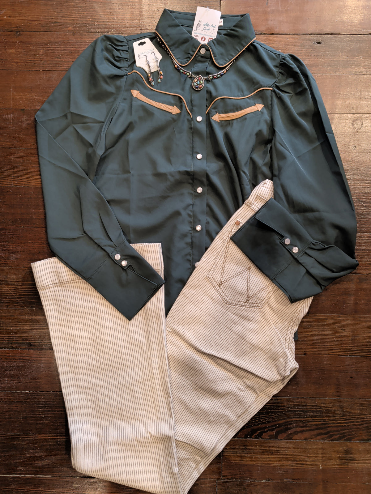 Howdy Hanny women's forest green pearl snap shirt with contrast Western piping, styled with tan pinstripe pants and matching jewelry.