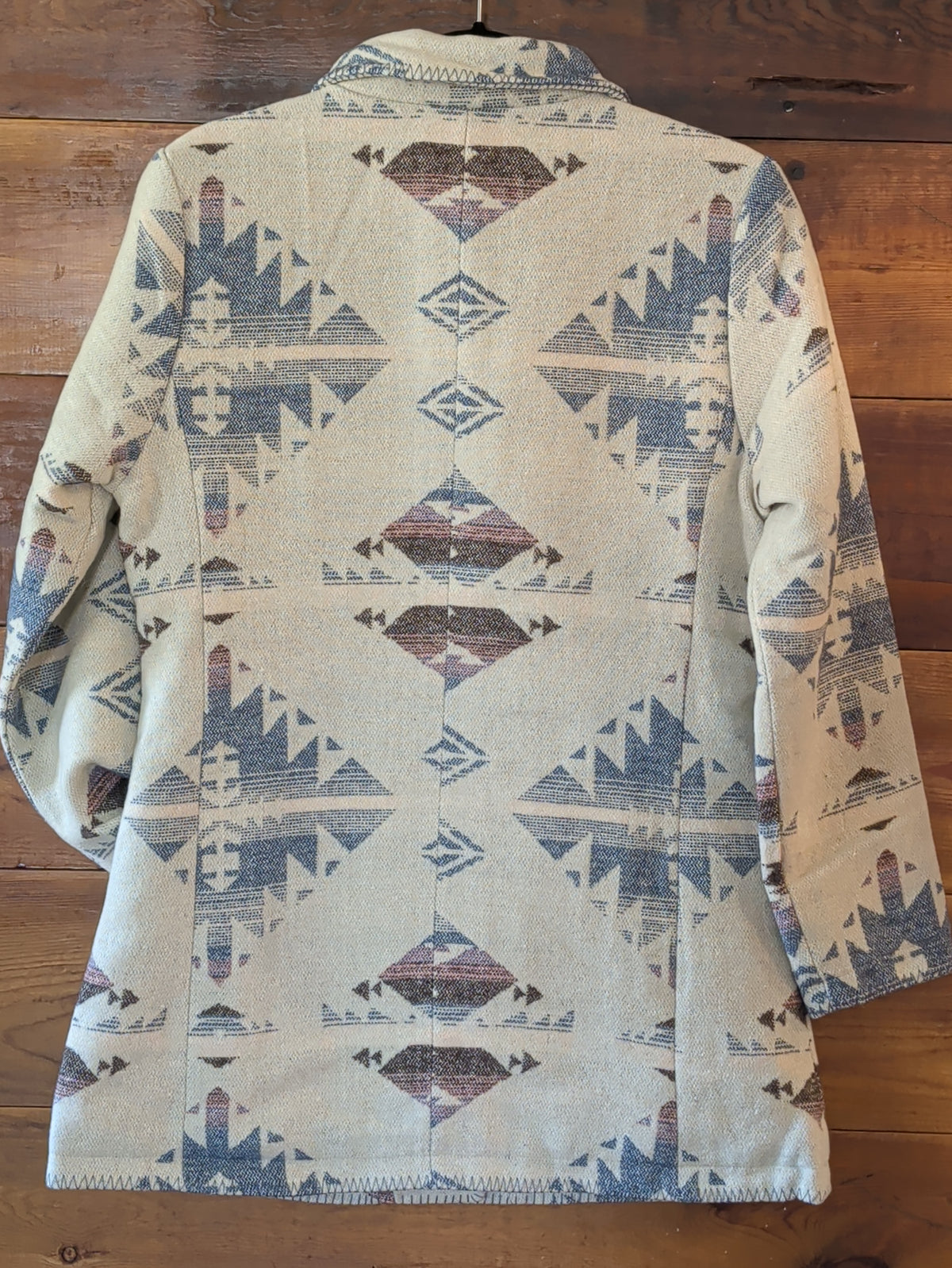 Back view of the cream Southwestern print coat showing long sleeves, geometric motifs, and blanket-stitched hem