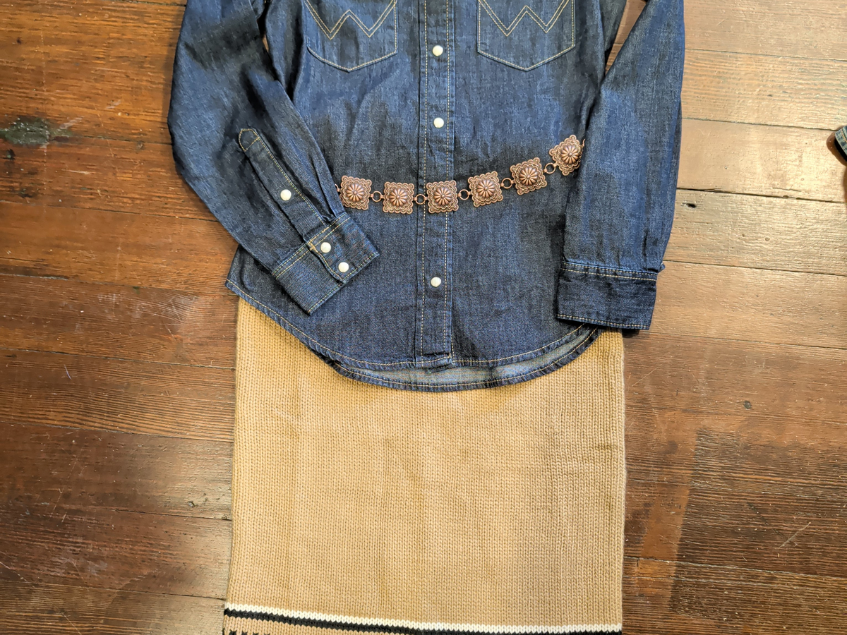 Close-up of light brown knit skirt styled with a dark denim shirt and decorative belt.