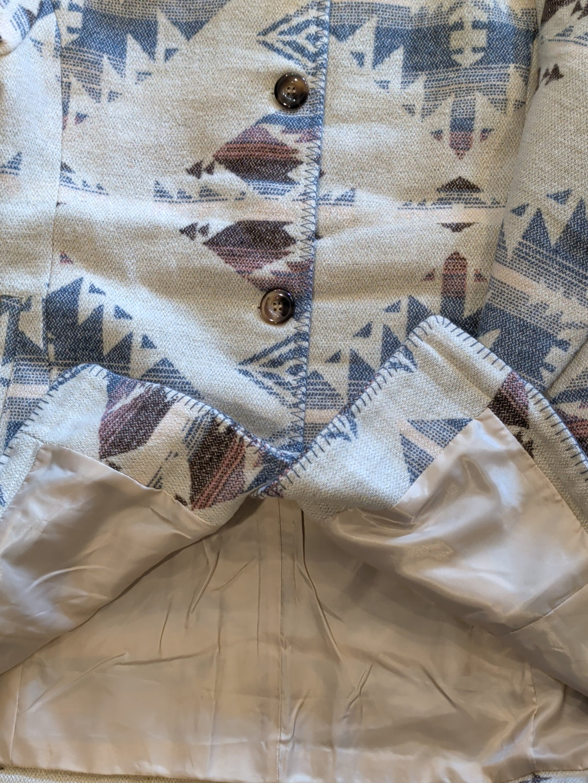 Inside view of the Southwestern print coat showing its full beige lining and blanket-stitched edges