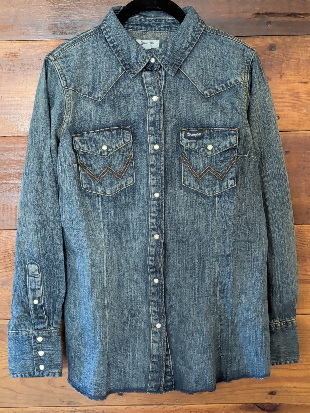Wrangler women’s blue denim Western snap shirt with long sleeves, pointed yokes and two snap-flap chest pockets.