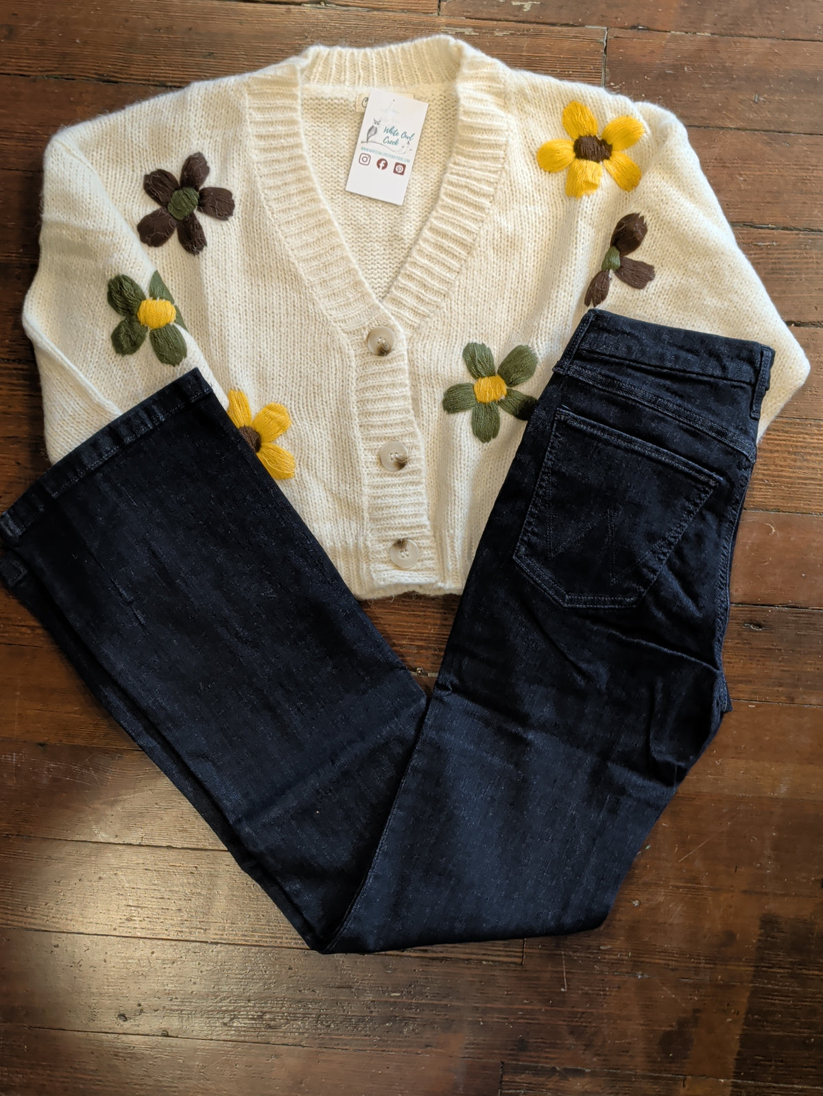 Wrangler Bespoke Camryn jeans folded to show the back pocket beside a cream floral cardigan.